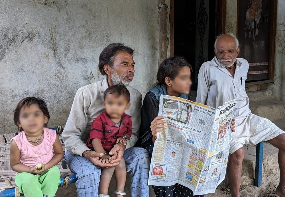 A young girl reading out newspaper to elders at her home.