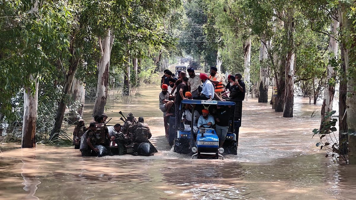 बाढ़ग्रस्त इलाके से गुजरते जवान और ट्रैक्टर पर सवार लोग.