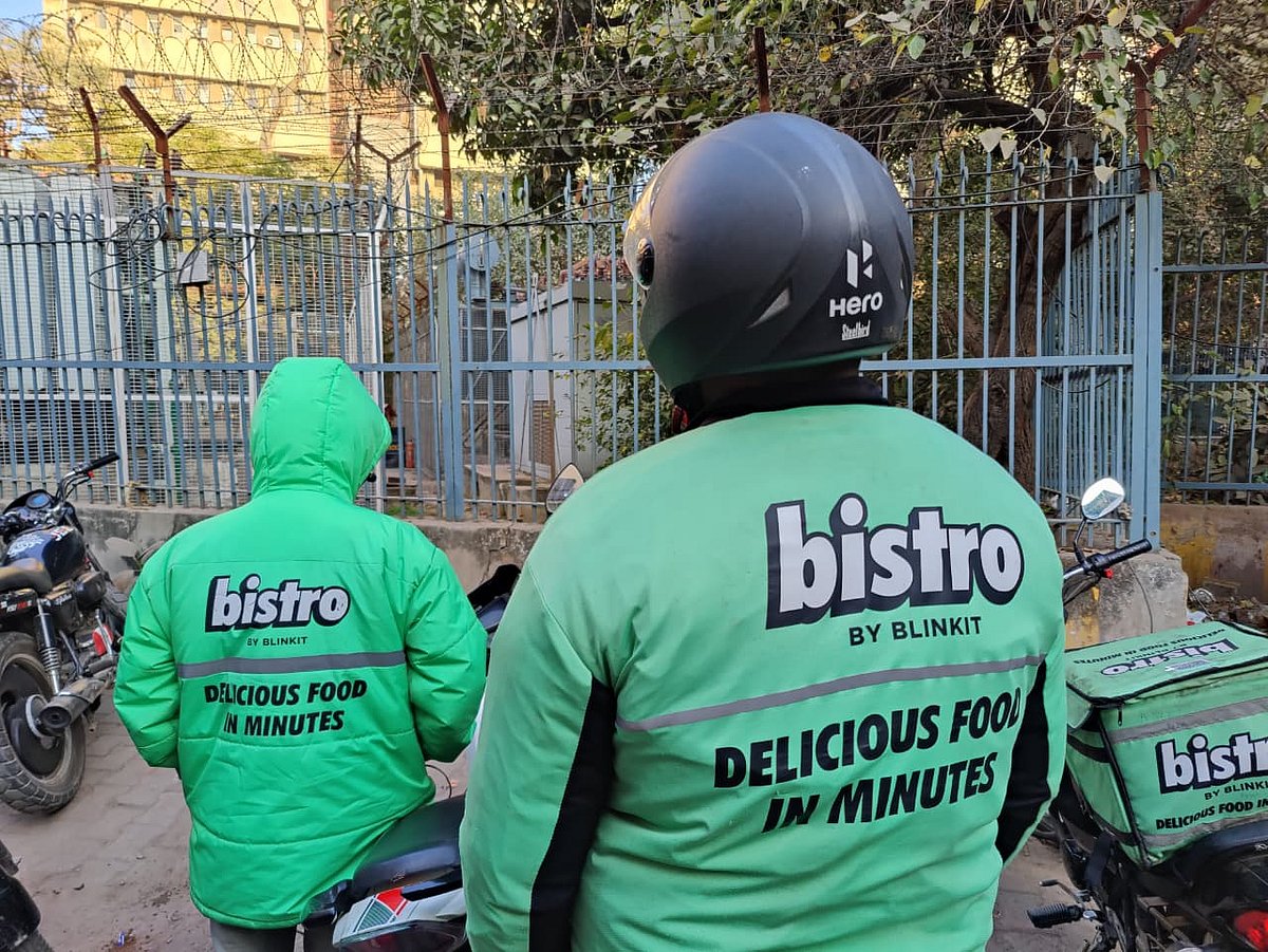 Bistro by Blinkit gig workers standing next to their scooters before a delivery. 