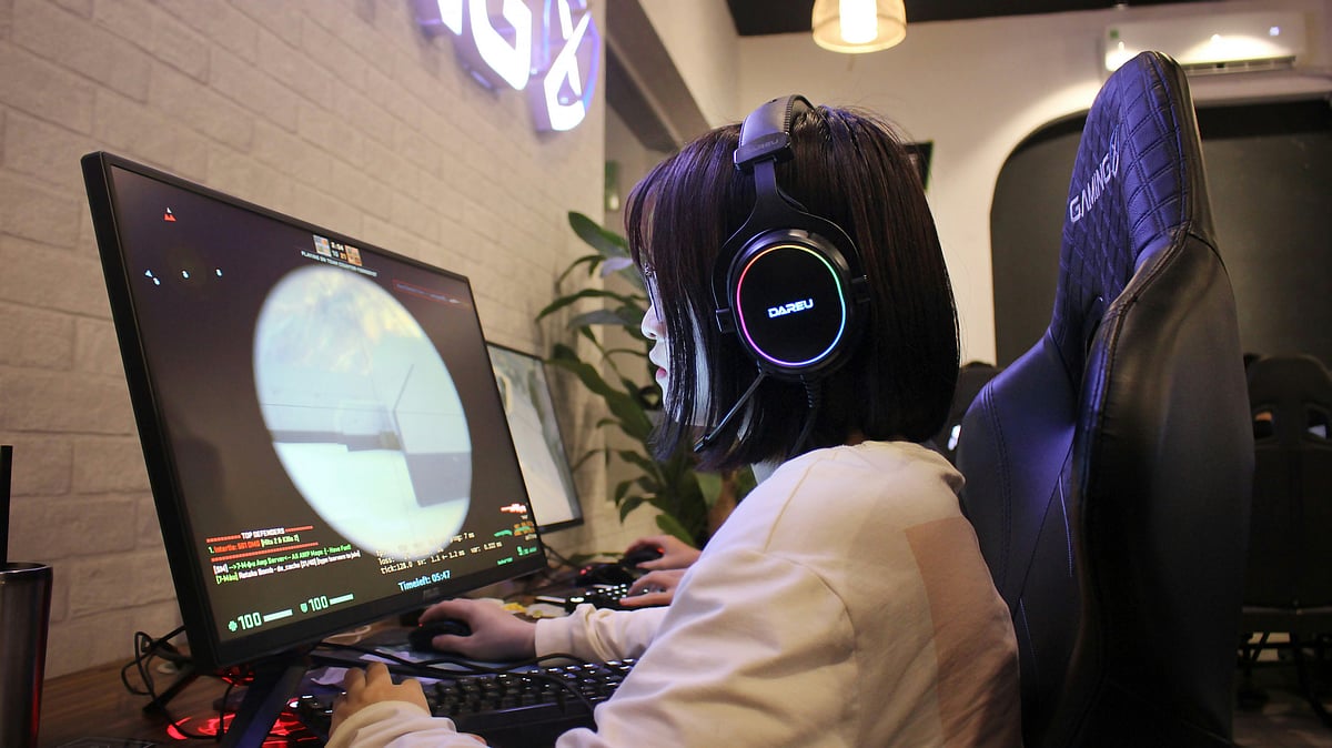 Gamer wearing RGB headset focused on playing a first-person shooter game on PC.