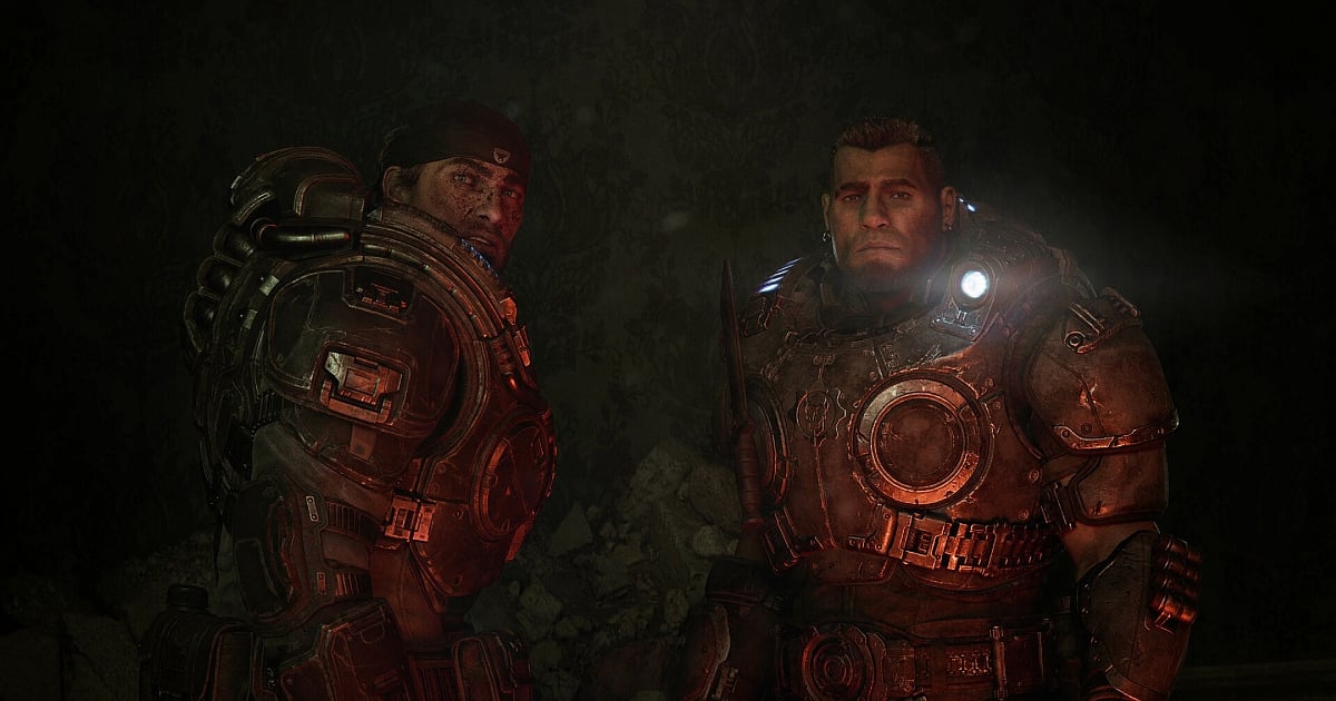 A cinematic still from Gears of War: E-Day featuring two soldiers are clad in heavy, battle-worn COG armor, standing in a dark, debris-filled room with ornate wallpaper in the background. On the left, looks over his shoulder with a grim expression, while On the right, stares forward with a look of intense determination. Red ambient light from below highlights the gritty textures of their armor and the soot on their faces.