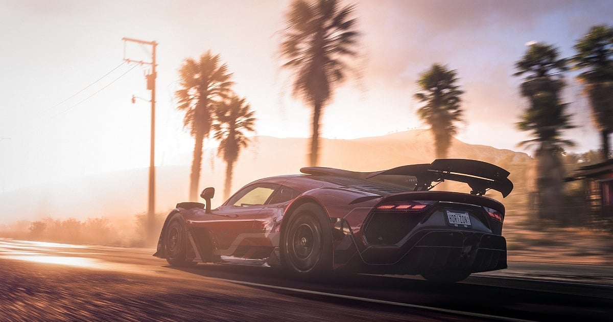 A high-performance red hypercar, resembling a Mercedes-AMG ONE, speeds down a desert highway during a hazy golden hour. The shot is taken from a low rear-quarter angle, emphasizing the car's aggressive aerodynamics and large rear wing, with motion blur on the road and passing palm trees to convey high speed against the glowing sunset.