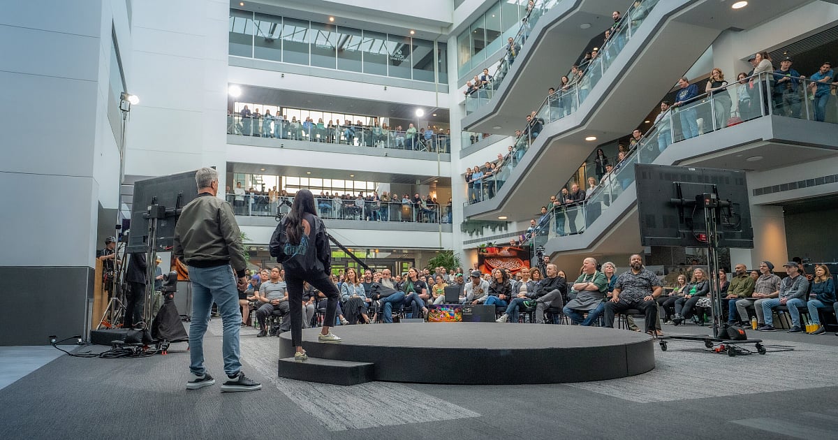 Matt Booty and Asha Sharma address employees in an office atrium