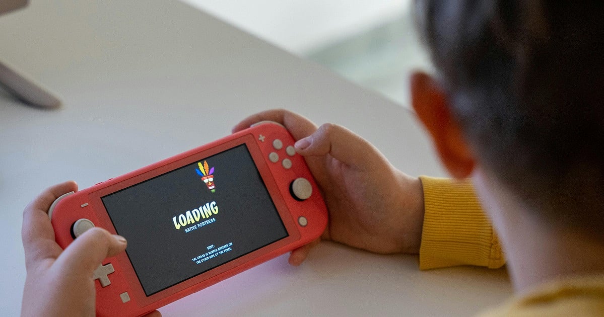 Person holding a handheld game console while a digital game loads on the screen