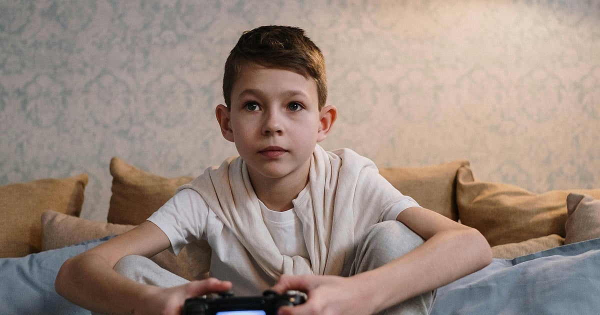 A child gaming on a couch with a DualShock controller