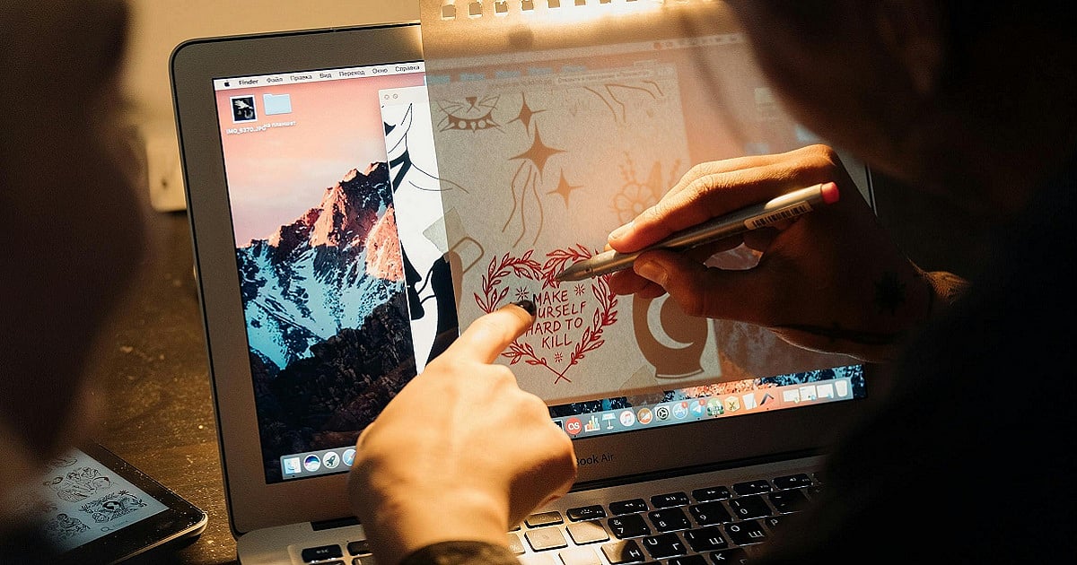 An artist sketches a design on a laptop, blending digital and traditional art techniques.