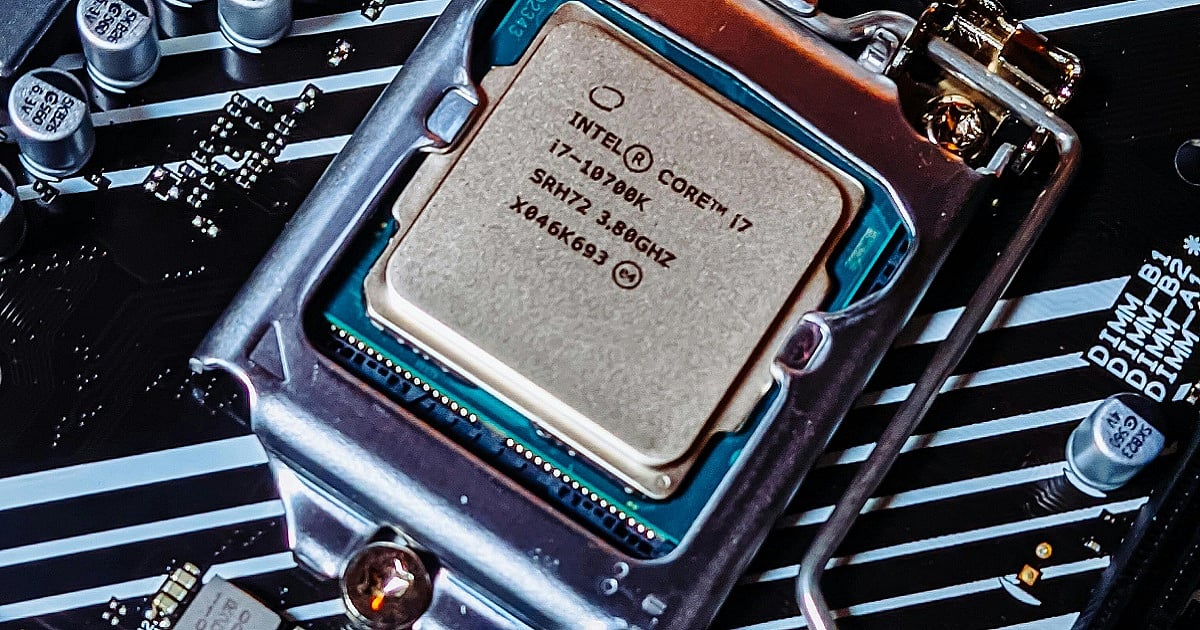 Close-up photograph of an Intel Core i7 desktop processor installed in an open CPU socket on a modern motherboard. The silver Intel chip, labeled “Intel Core i7,” is secured inside a metal retention bracket with the locking arm partially open.