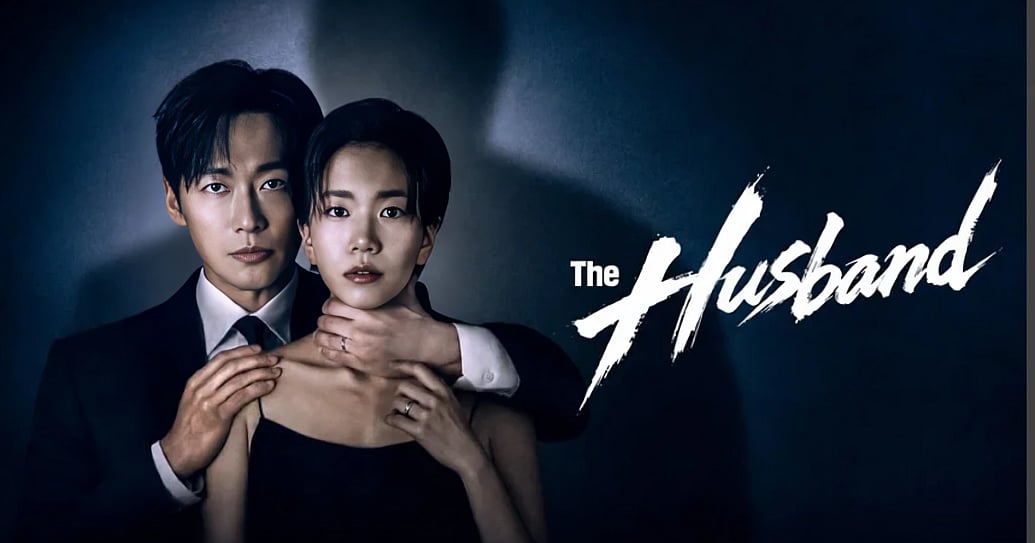 A dark, suspenseful promotional poster for "The Husband." On the left, a man in a black suit and tie stands behind a woman with short dark hair who is wearing a black spaghetti-strap dress. The man looks intensely at the camera with his left hand wrapped firmly around the woman's neck while his right hand rests on her shoulder. The woman has a tense, wide-eyed expression, holding onto his wrist with her right hand; both individuals wear wedding rings. A large shadow looms on the textured, dark grey wall behind them, and to the right, the title "The Husband" is displayed in a stark, jagged white brush font.