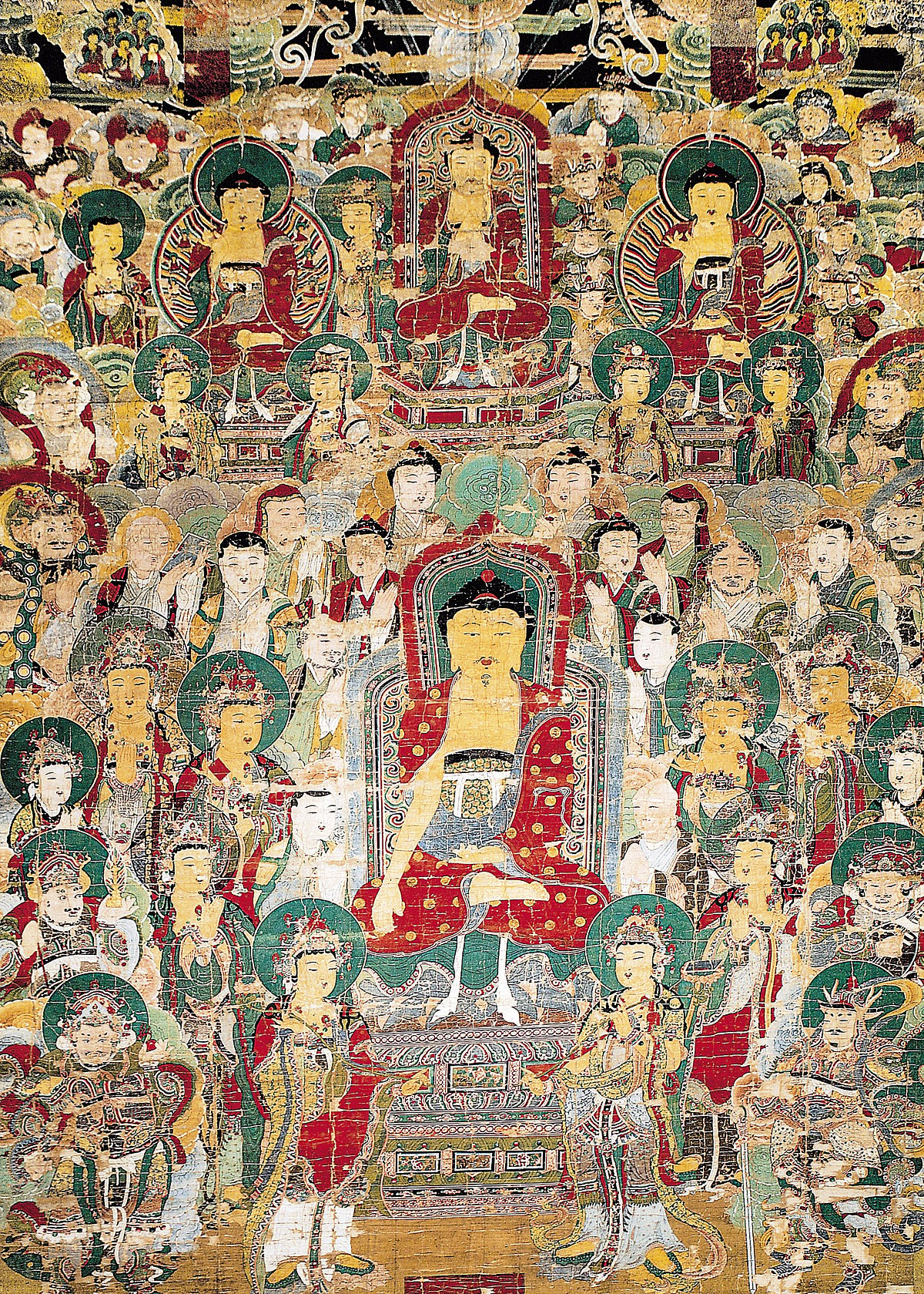 This huge hanging scroll depicting Shakyamuni Buddha and his followers would have been used to decorate an altar during open-air prayer gatherings held at and around Buseoksa Temple in Yeongju, Gyeongsangbuk-do. Hanging altar paintings are always enormous—sometimes more than 10 meters in height. Their large size not only allows them to be seen from a distance by the ceremony participants, but also emphasizes Buddha’s wondrous power and wisdom, which allows people’s aspirations to be realized. Large hanging scrolls like this one have rarely been found in China or Japan, leading experts to believe that their use is a tradition unique to Korean Buddhism. No one knows exactly when such paintings began to be produced, but most scrolls that remain today were made after the 17th century, suggesting that their use became widespread after the invasions of Japan and the Qing Dynasty, which devastated Joseon during the late 16th and early 17th century. Historians believe that the use of the scrolls and open-air prayer meetings were related with the nationwide efforts to console victims of the wars. This particular hanging scroll was painted for Buseoksa Temple in 1684, making it one of the earliest of its kind. The figure at the center of the painting is Sakyamuni Buddha, who is preaching the Lotus Sutra on Mt. Gridhrakuta. The Buddha is surrounded by his ten great disciples, Bodhisattvas, Sravakas (voice hearers), the four heavenly kings, and the Vajra Bearer. In the upper part, a Buddha triad is shown preaching, with Vairocana in the middle, Bhaisajyaguru on the left, and Amitabha on the right. The latter two Buddhas also form another triad with Sakyamuni below, as the Buddhas of the three realms.