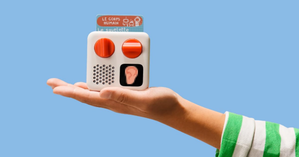 Yoto Mini portable audio player held in a child’s hand, featuring a KPop Demon Hunters audio card against a blue background.