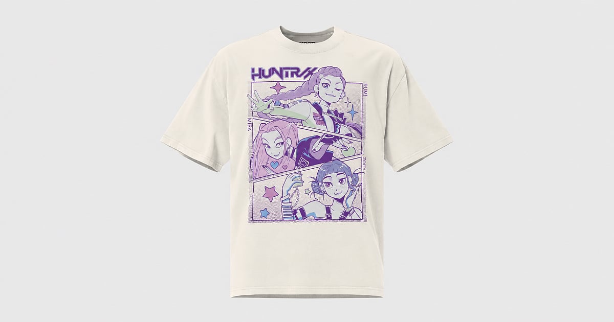Cream KPop Demon Hunters T-shirt featuring a purple HUNTR/X comic-style graphic of Rumi, Mira, and Zoey against a light gray background.