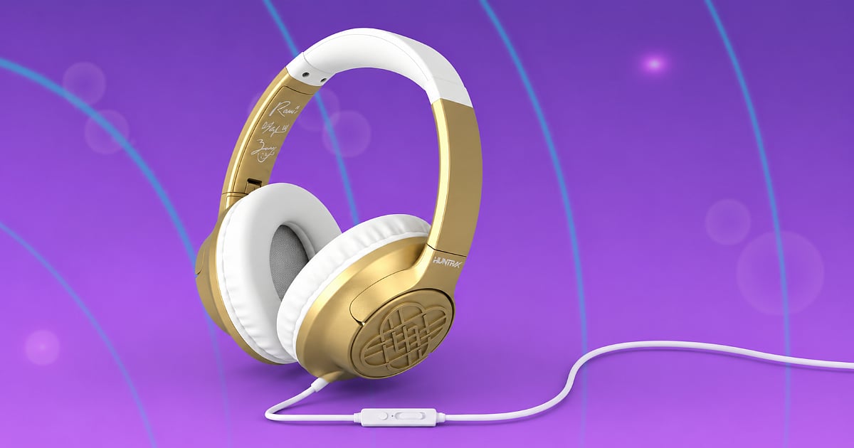 Gold-and-white HUNTR/X wired headphones with cushioned ear pads and an inline microphone against a purple background.