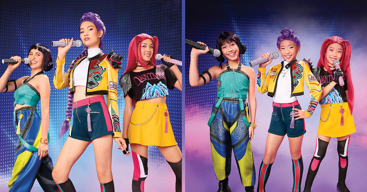 KPop Demon Hunters HUNTR/X-inspired costumes modeled by adults and children, featuring colorful stage outfits, character-inspired hairstyles, and microphones against a purple and blue performance backdrop.