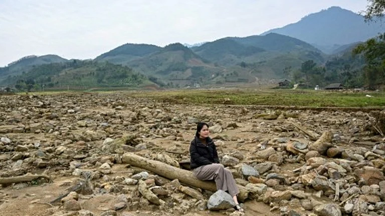 Nguyen Thi Kim sitting on a pillar of a destroyed house at the original site of Lang Nu village in Lao Cai province, after part of it was wiped away in a landslide triggered by Typhoon Yagi. - null