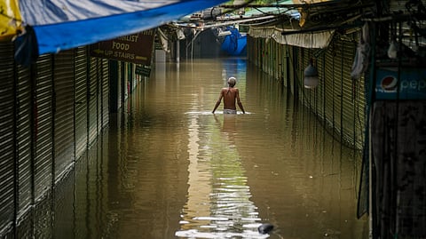 A man wades through waist-deep water in a flood-hit low-lying area near the Yamuna river in Delhi
