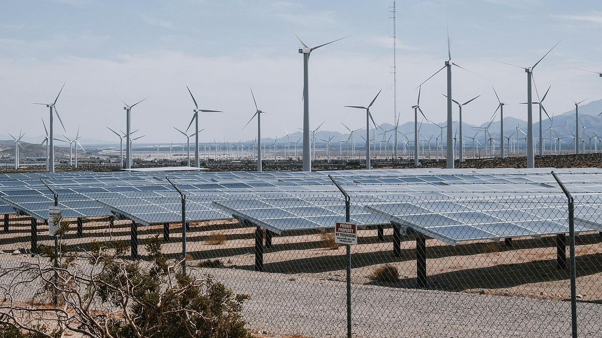 Wind turbines and solar panels at a hybrid renewable energy site - Photo by Kindel Media