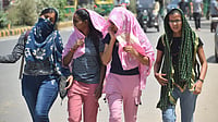 People shield themselves from intense sunlight during peak summer heat in Delhi