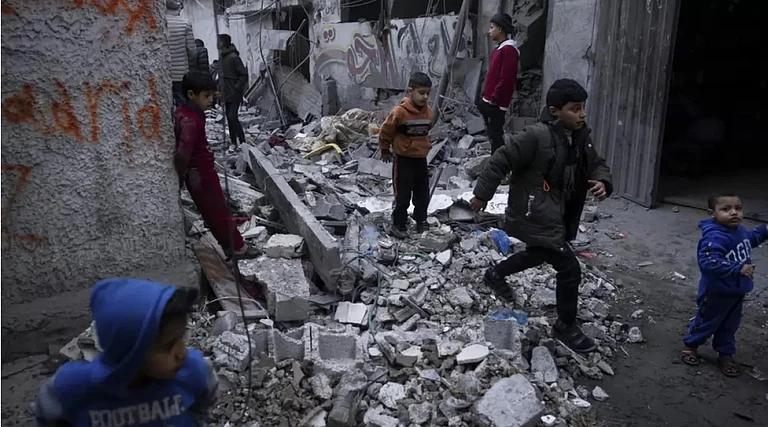 Palestinians look at the destruction after an Israeli strike in southern Gaza Strip - AP