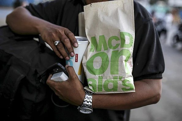 A customer carries take-out food from a McDonald's Corp. restaurant Representative Image/Getty Images