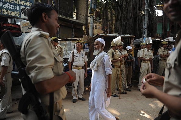 Suresh K Pandey/Outlook : An Indian Muslim man walks past paramilitary troops standing guard near a mosque in Ayodhya
