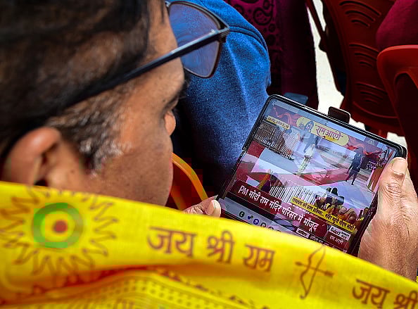 Getty Images : A devotee watches the consecration ceremony of the Ram Mandir on a phone during its consecration ceremony on January 22, 2024 in Ayodhya, India. 