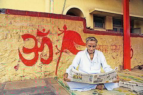 Imposing Backdrop: An elderly man reads a newspaper in Karnataka’s Bijapur