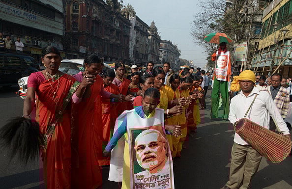 Getty Images : Indian tribal dancers perform on the street with vests bearing the image of PM Modi (2014) |