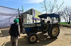 Tribhuvan Tiwari/Outlook India : Shubhkaran's tractor parked outside his house, against a poster with his photograph in Baloh village.