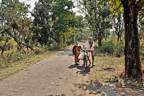 Different Lifestyle: An Adivasi couple walking towards their home