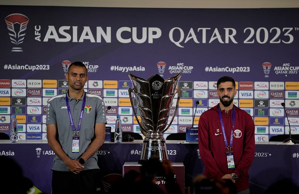 (AP Photo/Thanassis Stavrakis) : Jordan's Salem Al Ajalin, left, and Qatar's Hasan Al Haydos pose next to the Asian Cup trophy ahead of a press conference in Doha, Qatar, Friday, Feb. 9, 2024. Jordan will play Qatar on Saturday for the soccer final of the Asian Cup. 