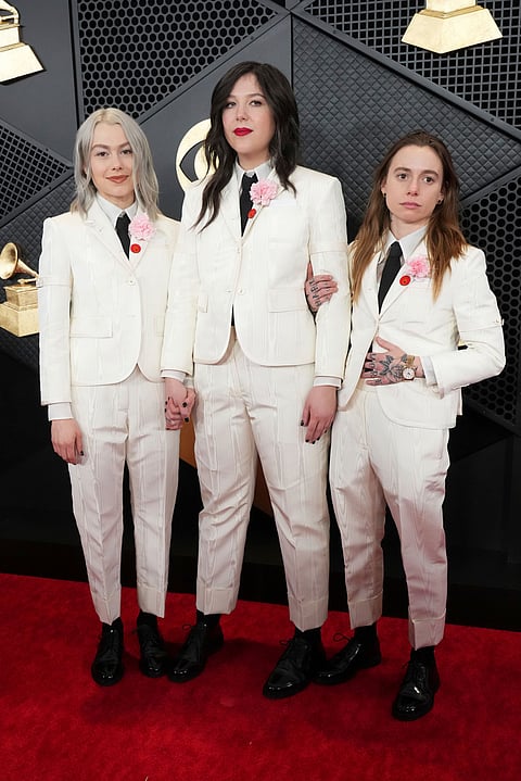Boygenius in matching cream-colored Thom Browne suits with red pins.