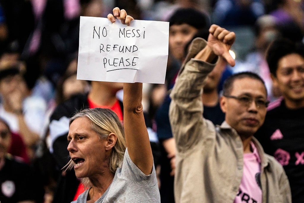 Photo: AP/Louise Delmotte : Fans react on Lionel Messi not taking the field during the friendly football match between Hong Kong XI and Inter Miami CF at the Hong Kong Stadium.