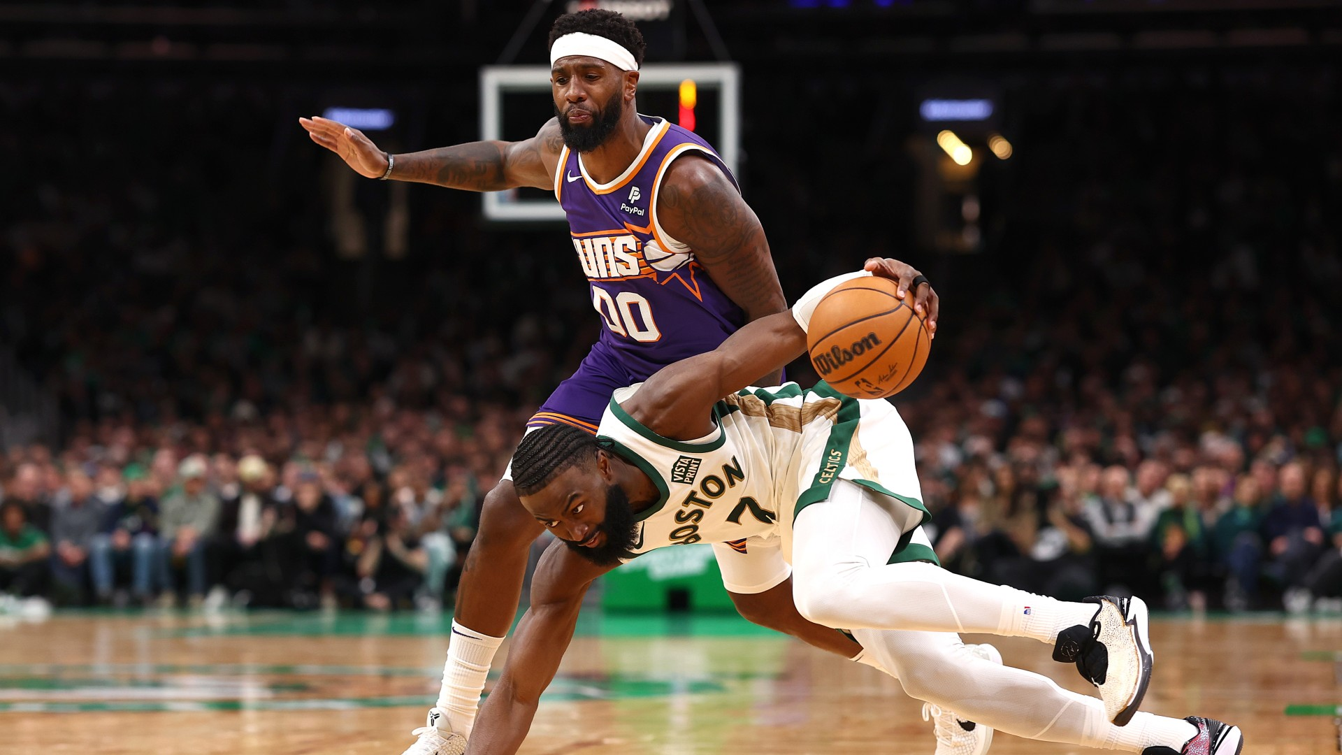 Jaylen Brown #7 of the Boston Celtics recovers with the ball after tripping ahead of Royce O'Neale #00 of the Phoenix Suns during the second half at TD Garden on March 14, 2024. - null
