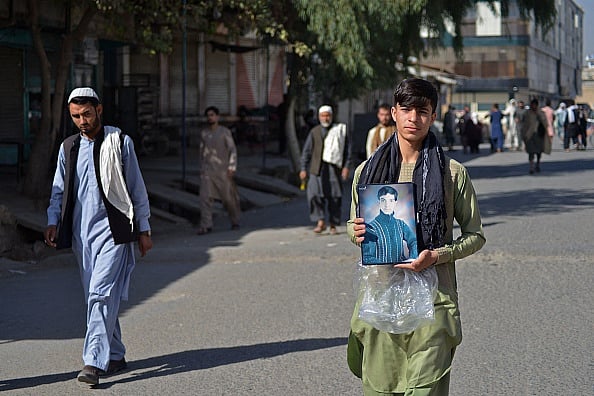 Getty Images : A man carries a picture of his relative to a graveyard in Kandahar on October 16, 2021, a day after 41 people were killed and scores were injured in a suicide bomb attack claimed by the Islamic State group in a Shiite mosque in Kandahar. 