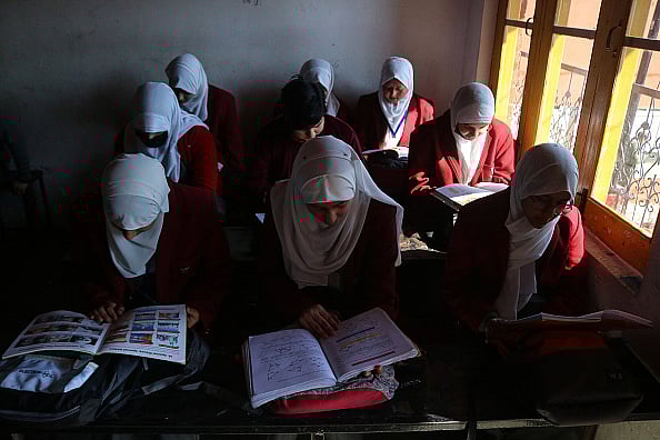 Firdous Nazir/ Eyepix Group/Future Publishing via Getty Image : Students read books in a classroom during the first day of classes after the resumption of school activities that were interrupted by the severe winter. Students across the valley head to their schools following a two-month-long winter break. 