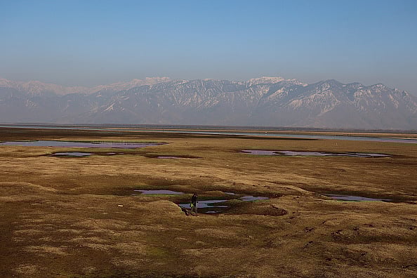 Getty Images : A boy is walking on the dried portion of Wular Lake in the Ningli area of Sopore District, Baramulla, Jammu and Kashmir, India, on February 14, 2024.
