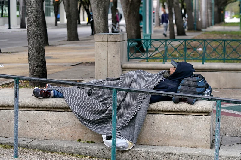 A man lies in a park covered with a blanket against the cold, Saturday, Jan. 29, 2022, in Miami. 