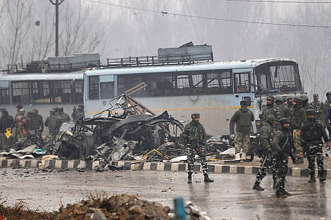 Security forces near the damaged vehicles at Lethpora on the Jammu-Srinagar highway, on February 14, 2019 in Srinagar, India