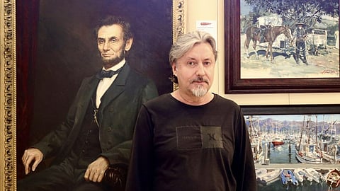 Artist Andrew Zabela-Zabelin stands next to his work inside Arrowhead Gallery in St. George, Utah.
