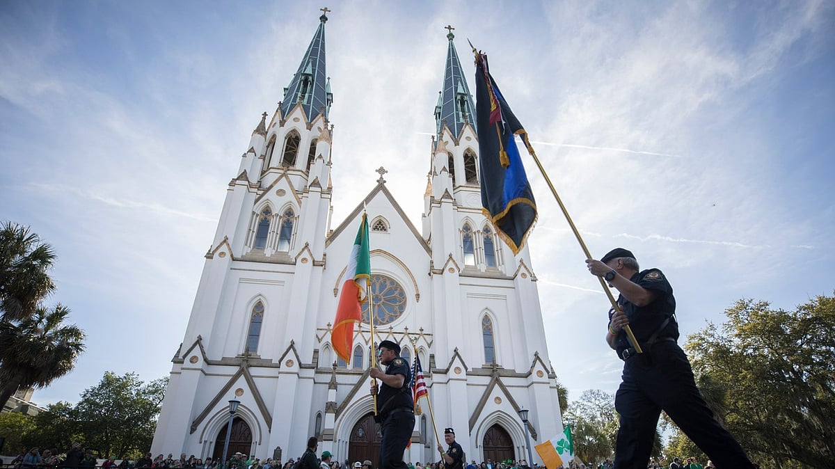 Participants carry flags past the Cathedral Basilica of St. John the Baptist while marching in the St. Patrick's Day parade last year. - AP