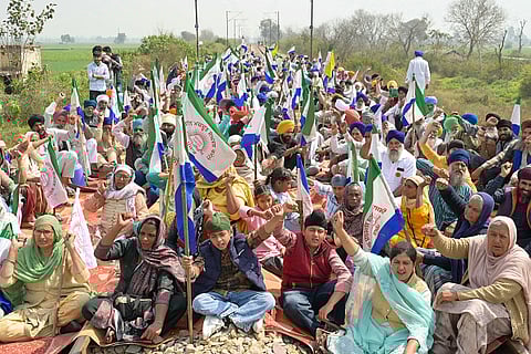 Farmers block railway tracks and shout slogans during a protest to demand minimum crop prices near a railway station on the outskirts of Amritsar on March 10, 2024.