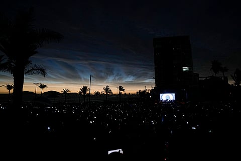People use their cell phones as the sky darkens during a total solar eclipse in Mazatlan, Mexico