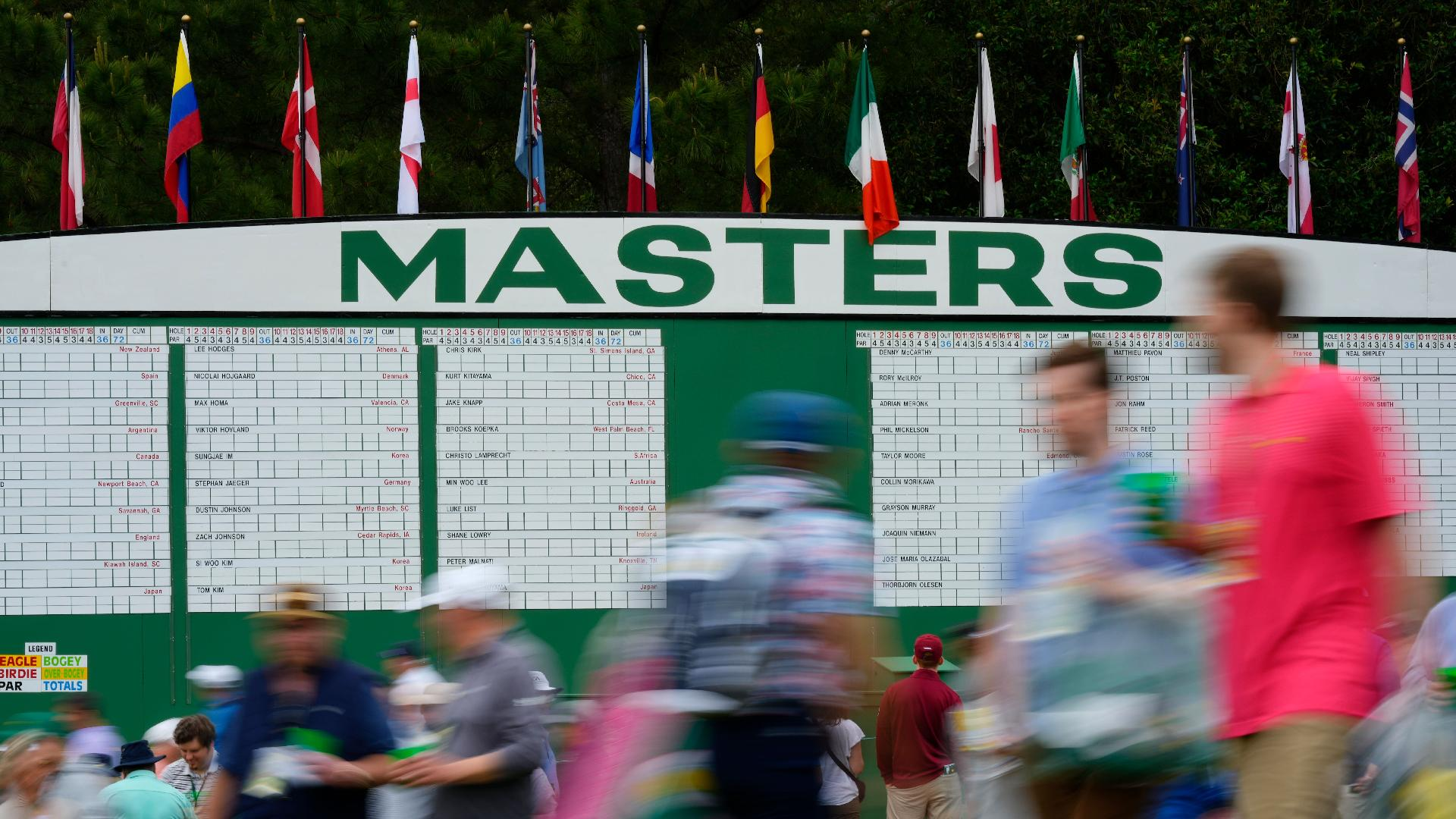 AP Photo/Matt Slocum : Patrons walk past the main scoreboard during a practice round.