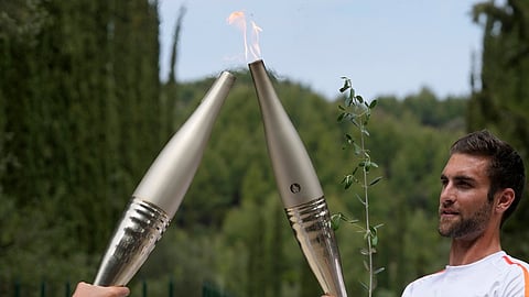 The first torch bearer, Greek olympic gold medalist Stefanos Douskos, right, passes the flame to first French torchbearer, three-time Olympic medallist Laure Manaudou, after the official ceremony of the flame lighting for the Paris Olympics, at the Ancient Olympia site, Greece.