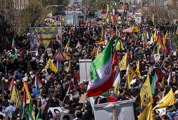 Getty Images : A crowd is carrying flags while participating in a rally to commemorate International Quds Day to mourn members of the IRGC Quds Force who were killed in an Israeli air strike in Syria
