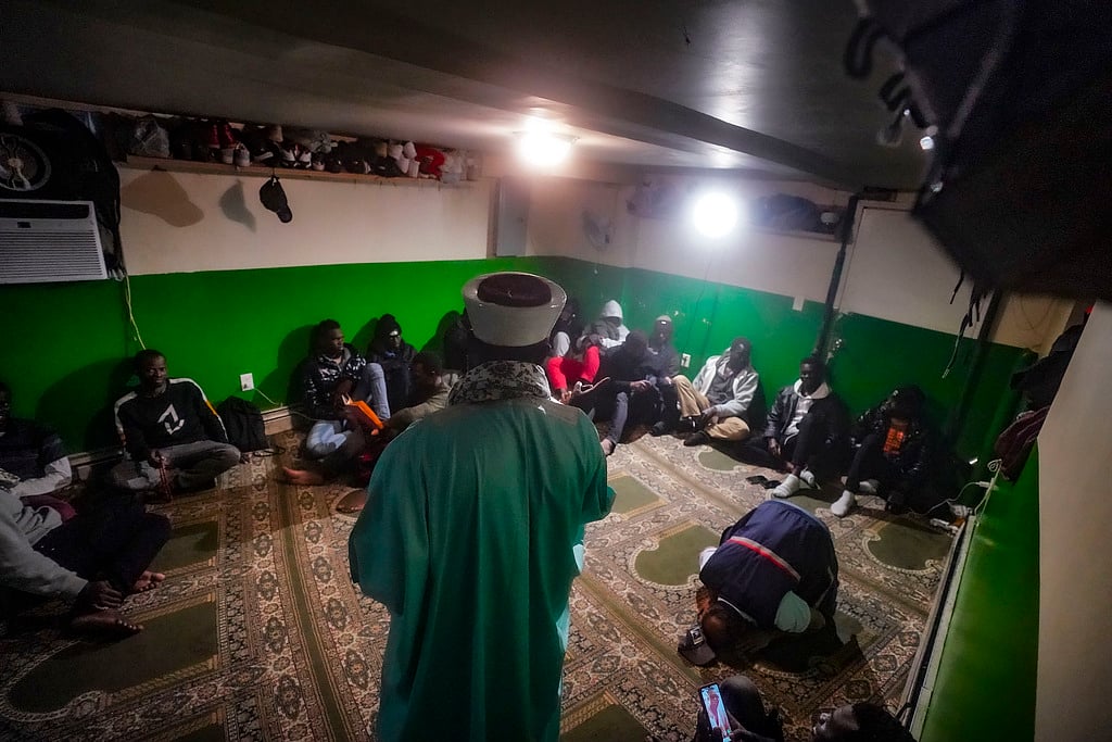 AP : Imam Omar Niass, center, speaks with Senegalese Muslim migrants, Friday March 15, 2024, at Bronx's Masjid Ansaru-Deen mosque in New York. Imam Niass has transformed the basement prayer space of the mosque, formerly his home, into a refuge for hundreds of migrants from Africa seeking asylum in the United States.