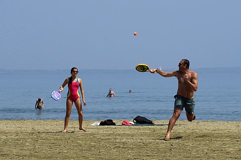 A man and woman play on the beach as other people enjoy the sea during a hot day in southern coastal city of Larnaca on the Mediterranean island of Cyprus, Sunday, March 31, 2024.