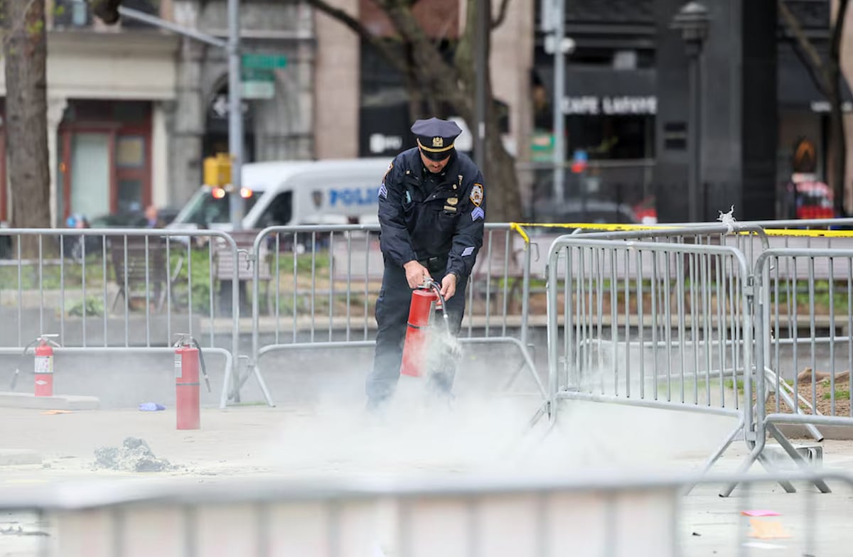  A police officer uses a fire extinguisher as emergency personnel respond to a report of a person covered in flames outside the New York courthouse.