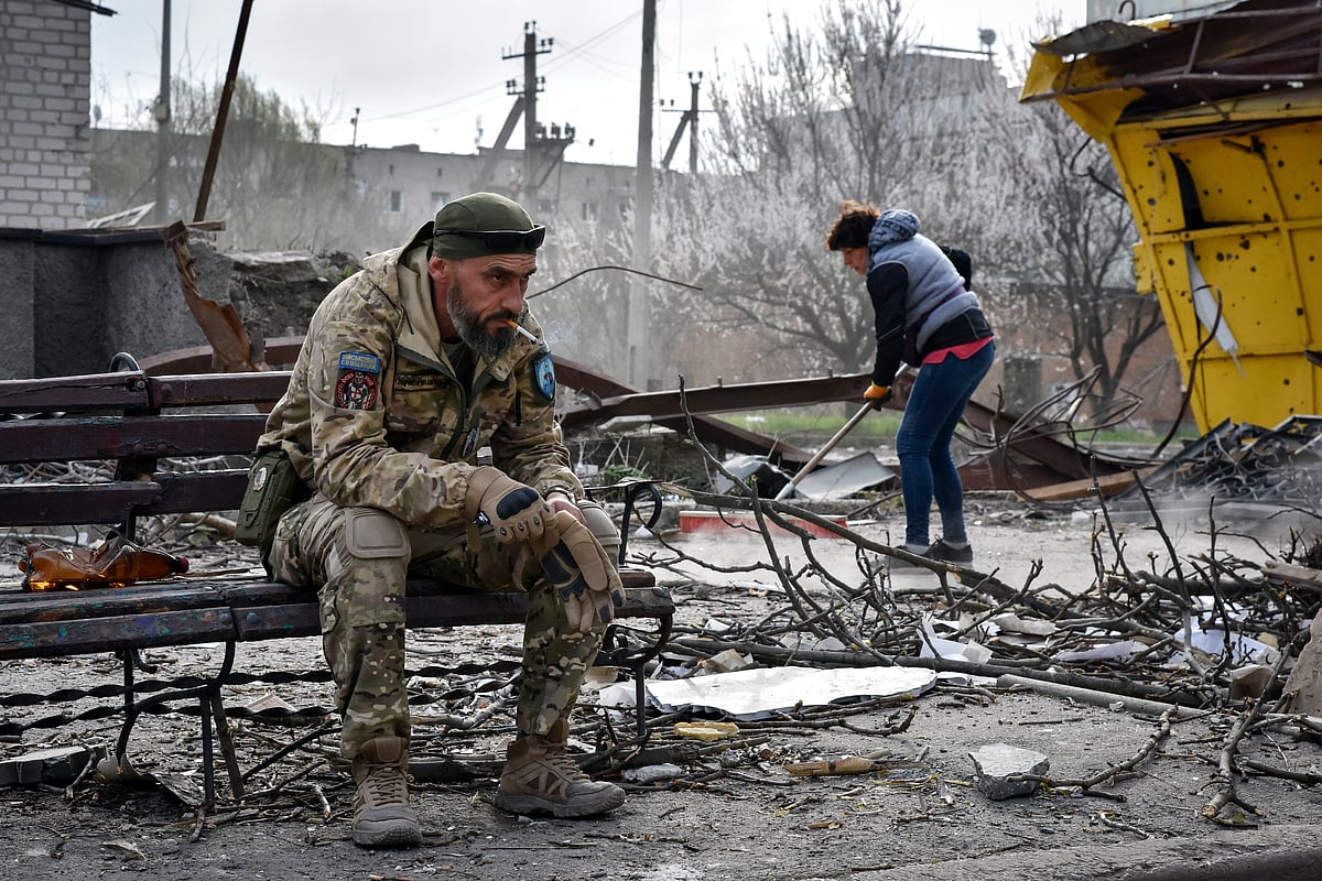 AP : A Ukrainian serviceman smokes sitting on a bench as a local resident clears debris near a building damaged in the Russian air raid in the town of Orikhiv, Zaporizhzhia region, Ukraine, Friday, Apr. 5, 2024. 