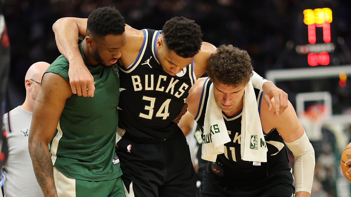 Giannis Antetokounmpo #34 of the Milwaukee Bucks is helped off the court by Thanasis Antetokounmpo #43 and Brook Lopez #11 after suffering an injury during the second half of a game against the Boston Celtics at Fiserv Forum on April 09, 2024. - null